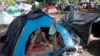 Una migrante en una tienda de campaña espera su permiso de tránsito para atravesar Honduras hacía Guatemala en su ruta a EEUU, en octubre de 2023. (AP/Elmer Martinez)