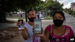 Servilia Pedroso (der.), madre del estudiante de 18 años Eloy Bárbaro Cardoso, y Yaquelin Cruz, madre de Dariel Cruz, dos manifestantes del 11J en La Güinera que fueron encarceladas, muestran sus fotos. (AP/Ramón Espinosa)