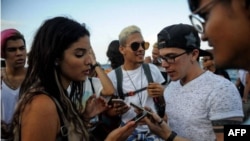 Jóvenes cubanos verifican conexión a internet en sus móviles en La Habana.