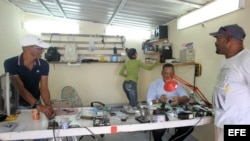 Un hombre arregla un celular en su negocio de reparación hoy, viernes 19 de diciembre de 2014, en La Habana (Cuba).