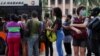 Cubanos hacen fila para subir a un transporte en La Habana.
