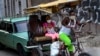 Usando máscara de protección contra el coronavirus, un hombre trasporta a clientes en un bicitaxi en La Habana. (AP/Ramon Espinosa).