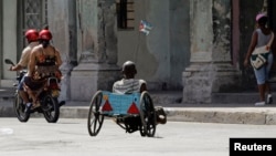 Un hombre con discapacidad se traslada en una silla de ruedas improvisada. REUTERS/Desmond Boylan