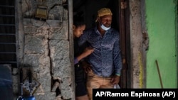 Emilio Román, padre de dos jóvenes y una hija que se encuentran en prisión acusados de participar en las recientes protestas contra el gobierno, posa con su nuera María Carla Milan Ramos en su casa en el barrio habanero La Güinera.