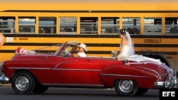 Una pareja de recién casados viaja en un viejo auto descapotable en La Habana (Cuba).