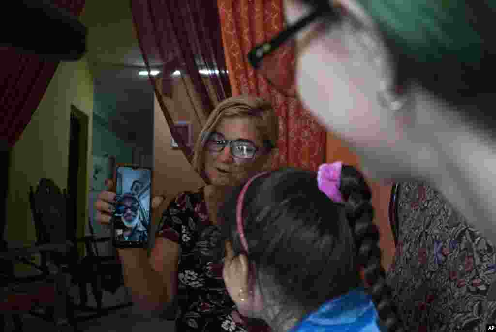 Danmara Triana sostiene su celular durante una videollamada con su esposo Roberto de la Iglesia, quien vive en Estados Unidos desde 2015 con su hijo.  (AP Foto/Ramón Espinosa)