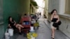 Una mujer camina mientras habla por teléfo calle de Santa Clara, provincia de Villa Clara, Cuba, el 11 de septiembre de 2023. (Foto de ADALBERTO ROQUE / AFP)