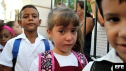Tres niños posan con una bandera cubana durante el primer día del curso escolar.