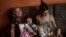 Danmara Triana (izquierda), con sus hijas Alice (centro) y Claudia, muestran fotos suyas con su hermano y su padre, quienes emigraron a Estados Unidos en 2015. (AP Foto/Ramón Espinosa)