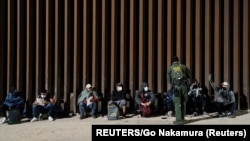 Migrantes de Venezuela y Cuba detenidos por la patrulla fronteriza de EEUU después de cruzar la frontera desde México en Yuma, Arizona el 17 de febrero de 2022.