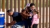 Una madre migrante cubana le da agua a su hija tras cruzar la frontera por el muro que separa a Estados Unidos y México, en Yuma, Arizona. RINGO CHIU / AFP/Archivo)