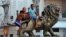 Varios niños juegan en la estatua de un león en el Paseo del Prado de La Habana (Cuba).