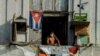 Un hombre se asoma a un balcón, en La Habana, con una máscara para protegerse del coronavirus. (Foto: Yamil Lage/AFP).