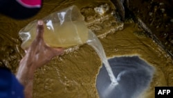 Un trabajador mexcla agua con oro y mercurio en una hoja de aluminio en una mina de oro de El Callao.